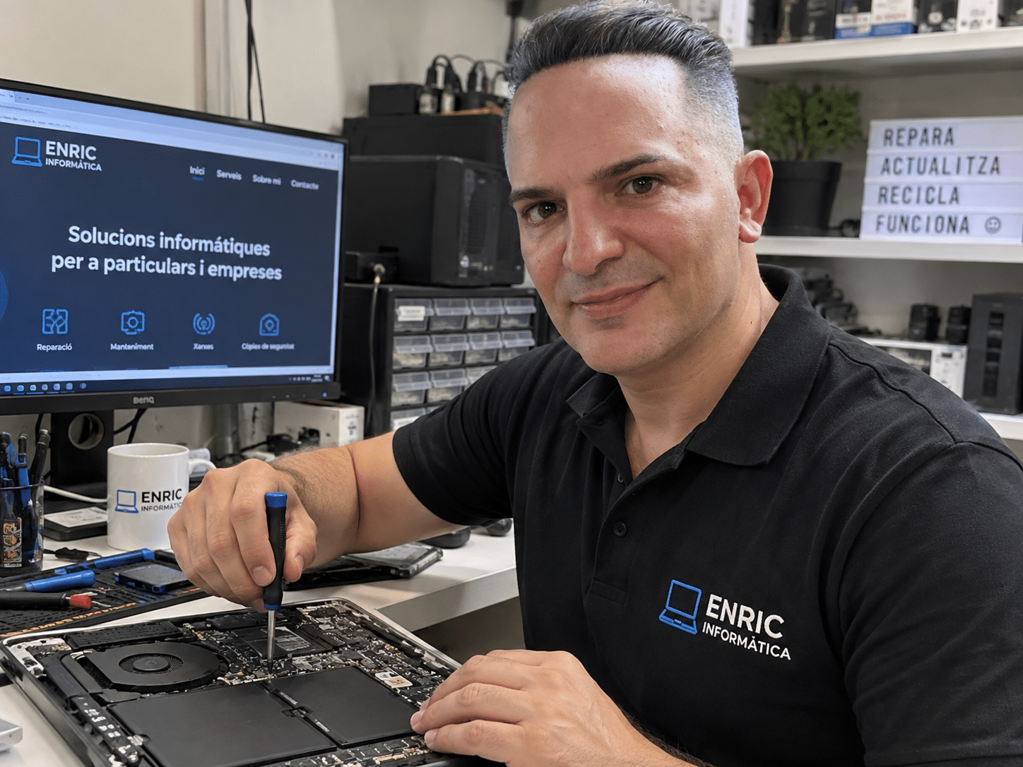Enric revisando un ordenador portátil en su taller de Enric Informática